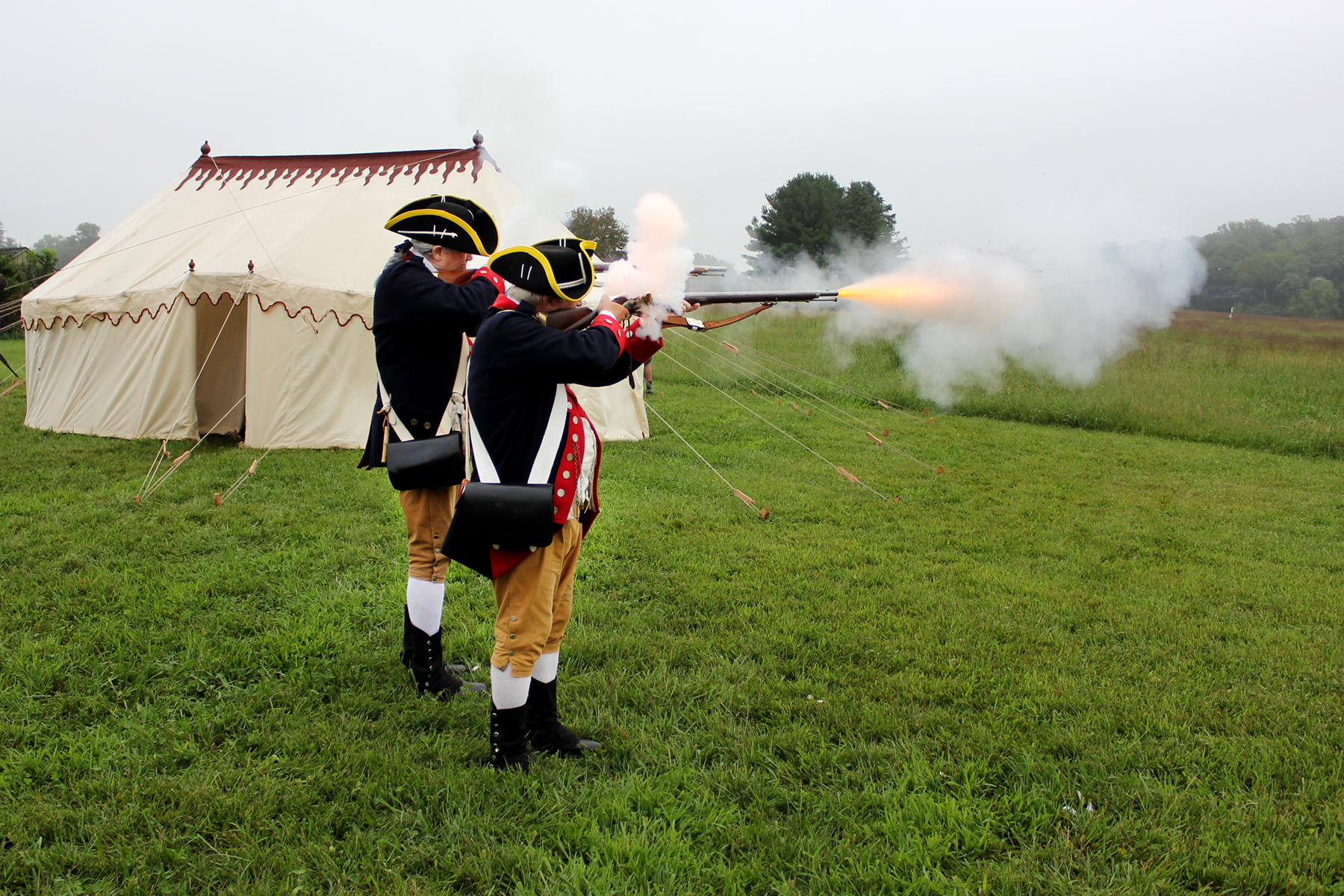 Reenactors from the 1st Delaware Regiment firing off a few rounds from their muskets, with a replica of George Washington’s tent in the background, courtesy of the Museum of the American Revolution.