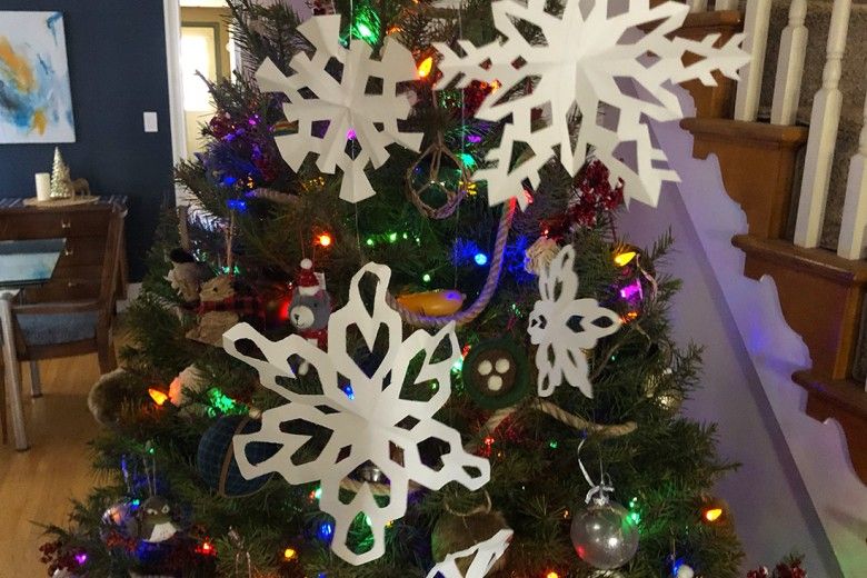 Paper snowflakes hung up in front of a Christmas tree