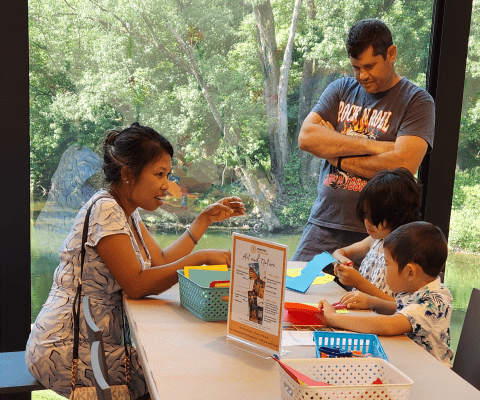 A husband and wife and their 2 kids sit at a table doing crafts.