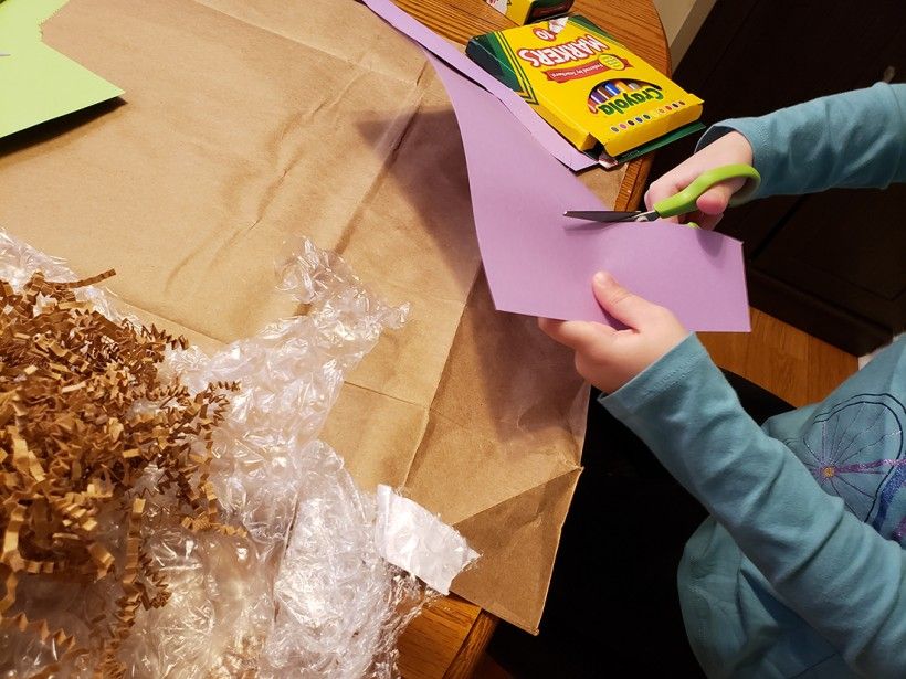 A young girl using scissors to cut up a piece of construction paper
