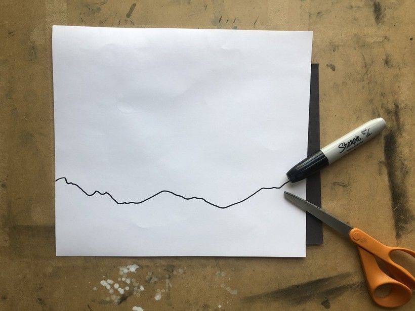 Black horizon line drawn onto a piece of white paper
