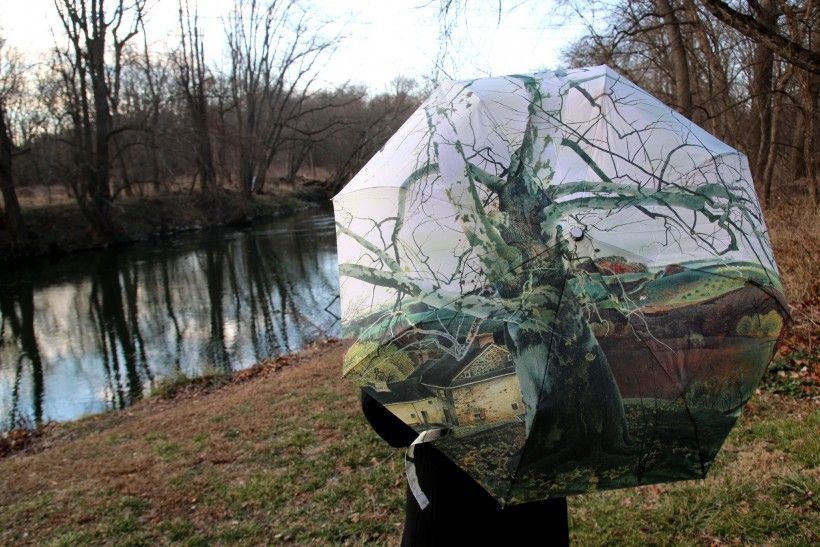 Woman modeling an umbrella featuring artist Andrew Wyeth's painting entitled Pennsylvania Landscape next to the Brandywine River
