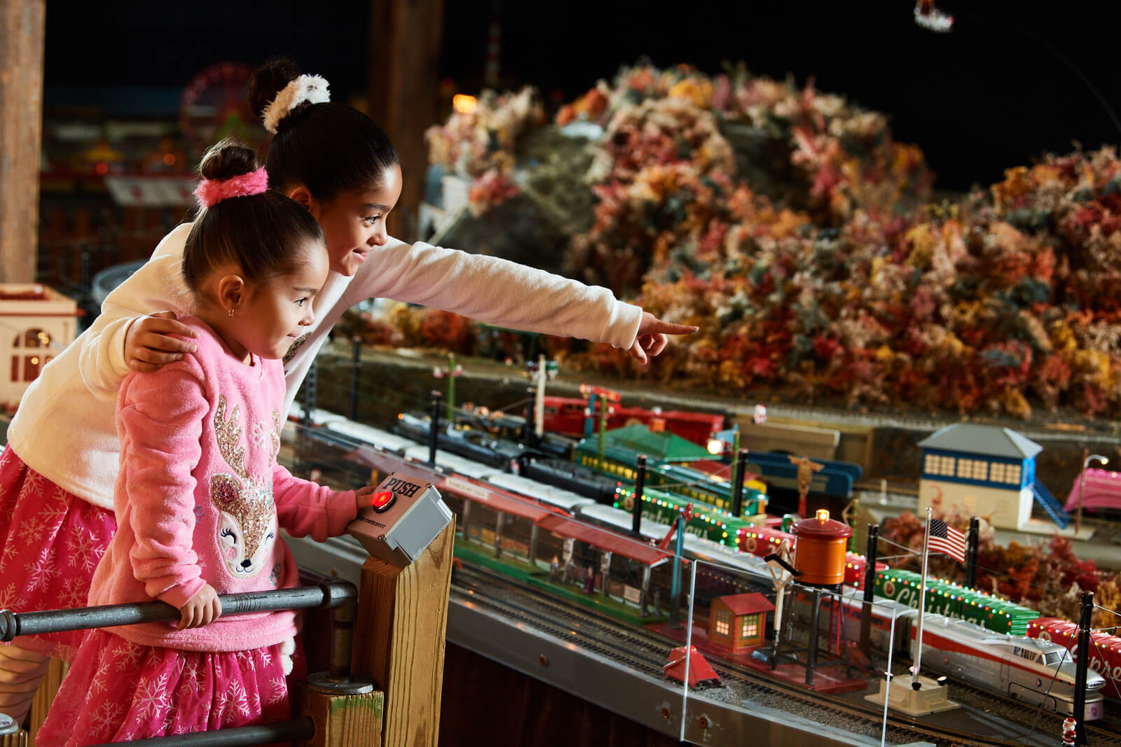 Two kids looking and pointing at the model trains.