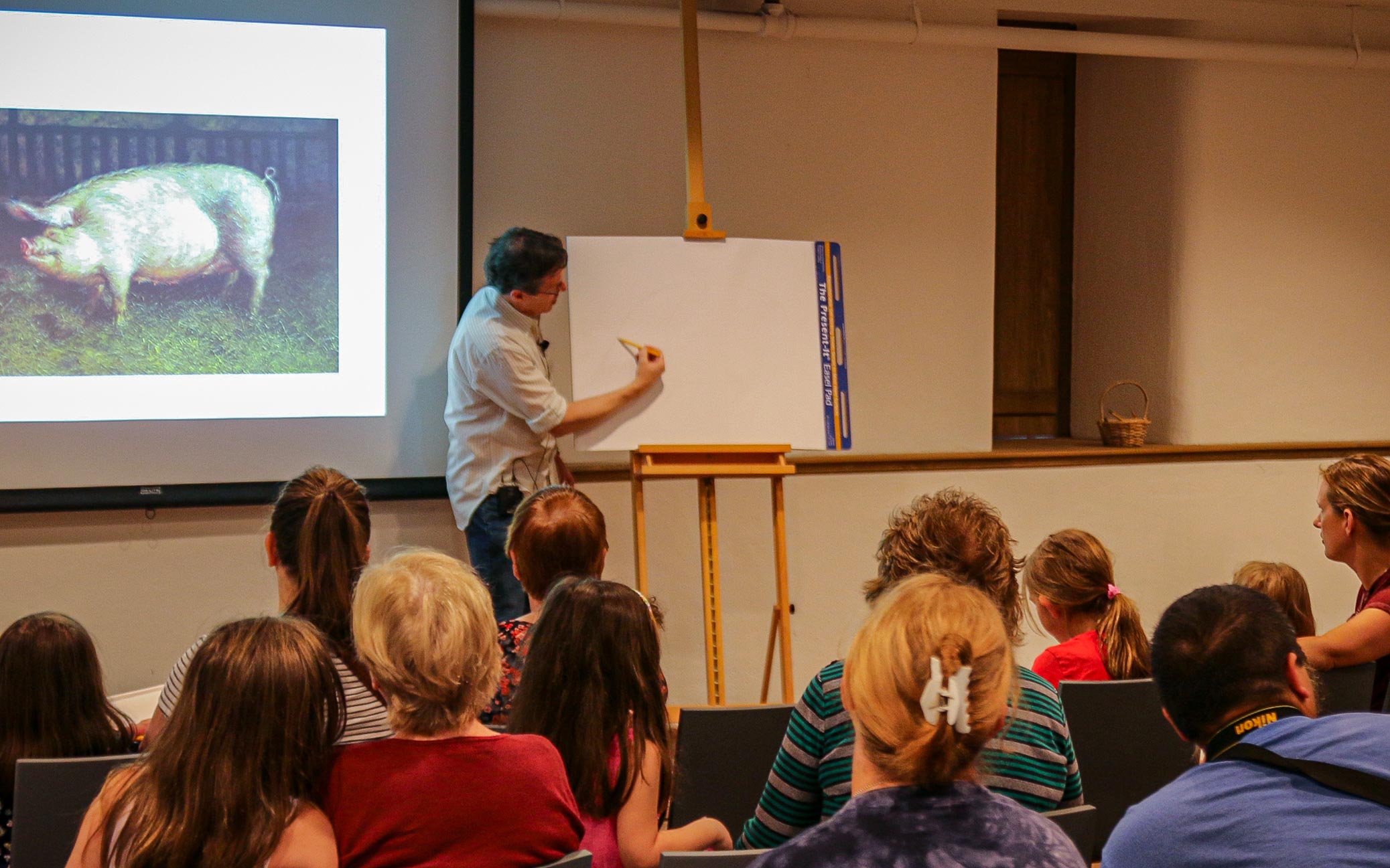 A man sketching in front of an audience.