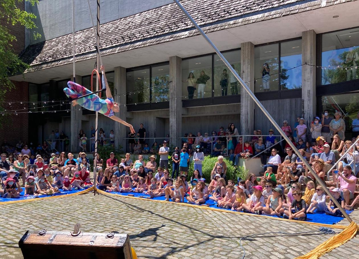 A circus performing outside in the Museum courtyard surrounded by an audience.