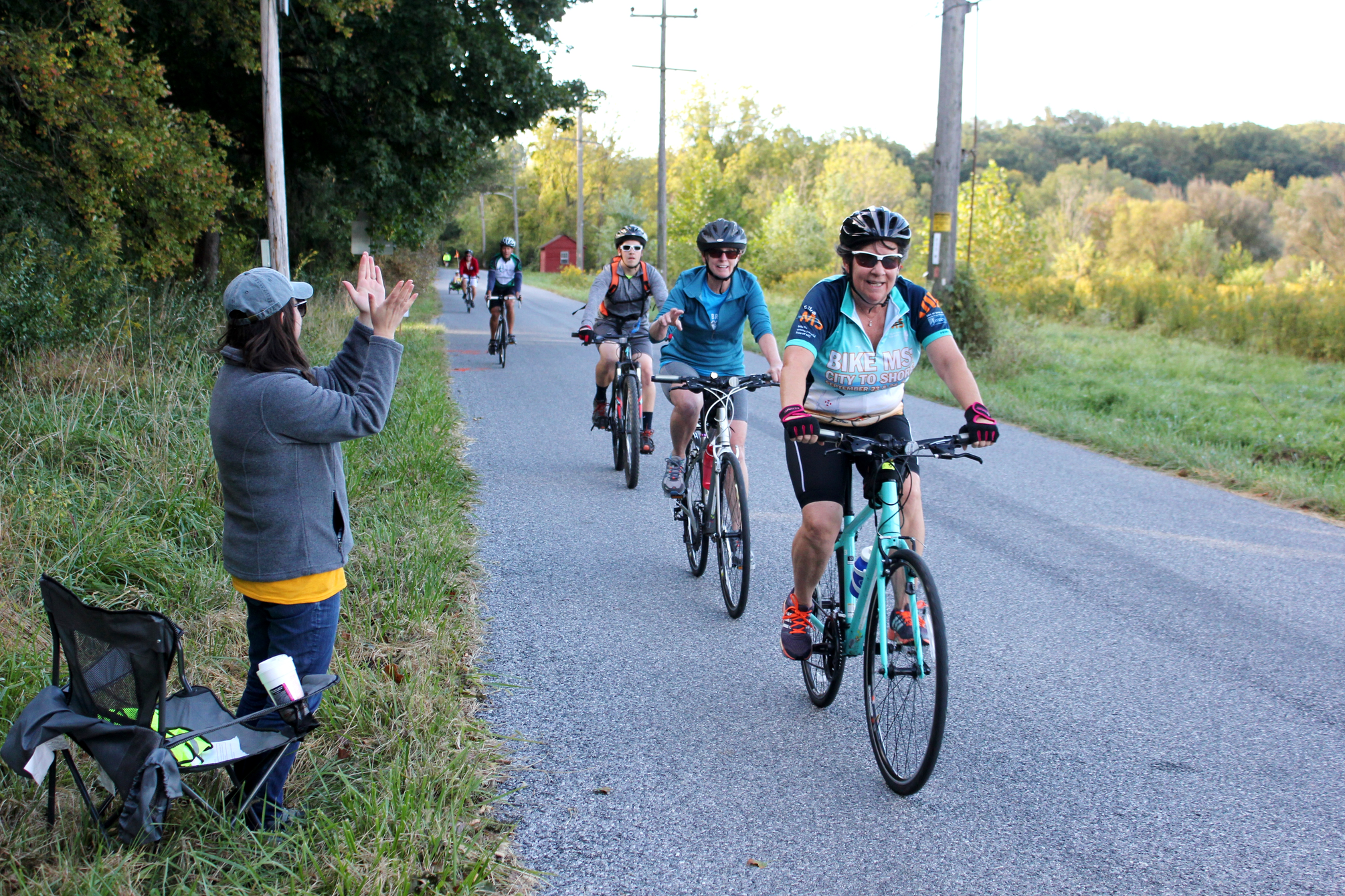 Cyclists traveling along road during "Bike the Brandywine" event and being cheered on by a bystander
