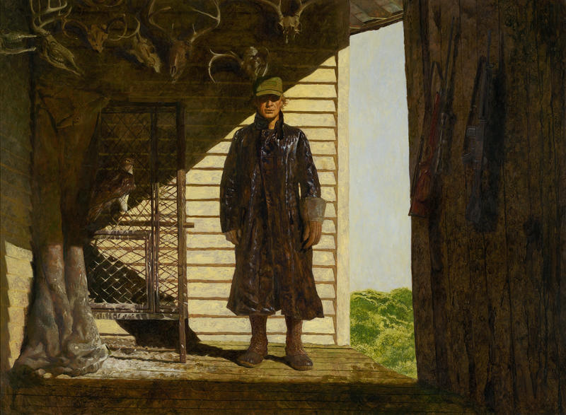 Man in a trench coat standing on his porch on a sunny day in dark clothing. 