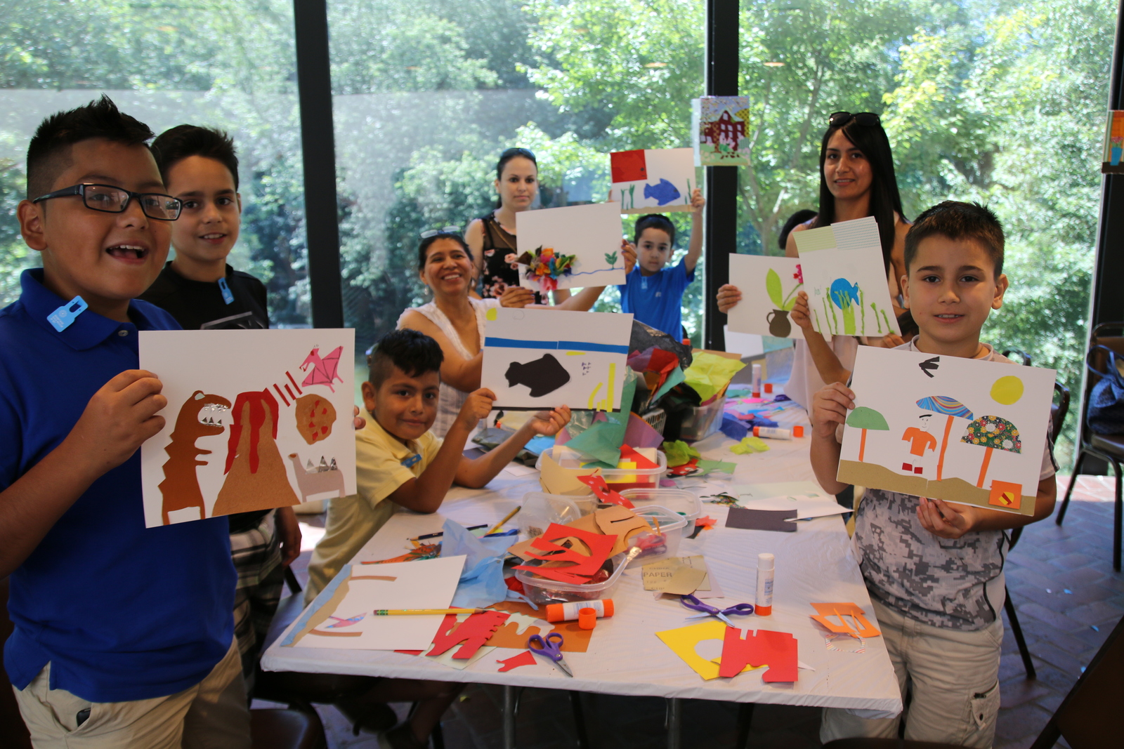 children holding up pictures they have drawn on a first free Sunday in the cafe at the Museum