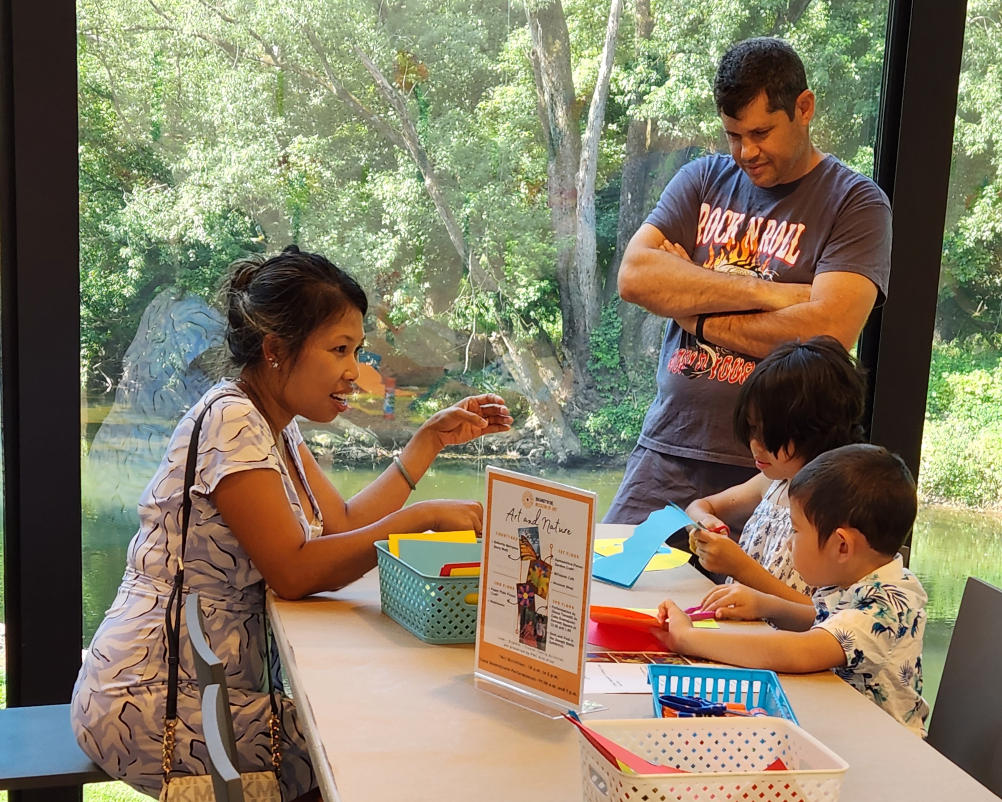 A husband and wife and their 2 kids sit at a table doing crafts.