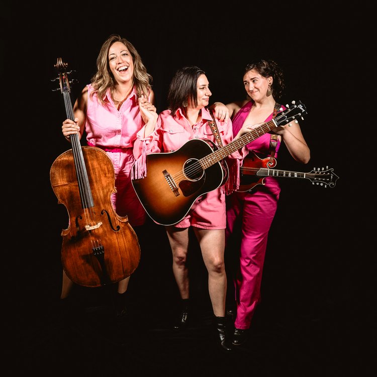 square photo with black background showing three female musicians wearing pink and holding their instruments