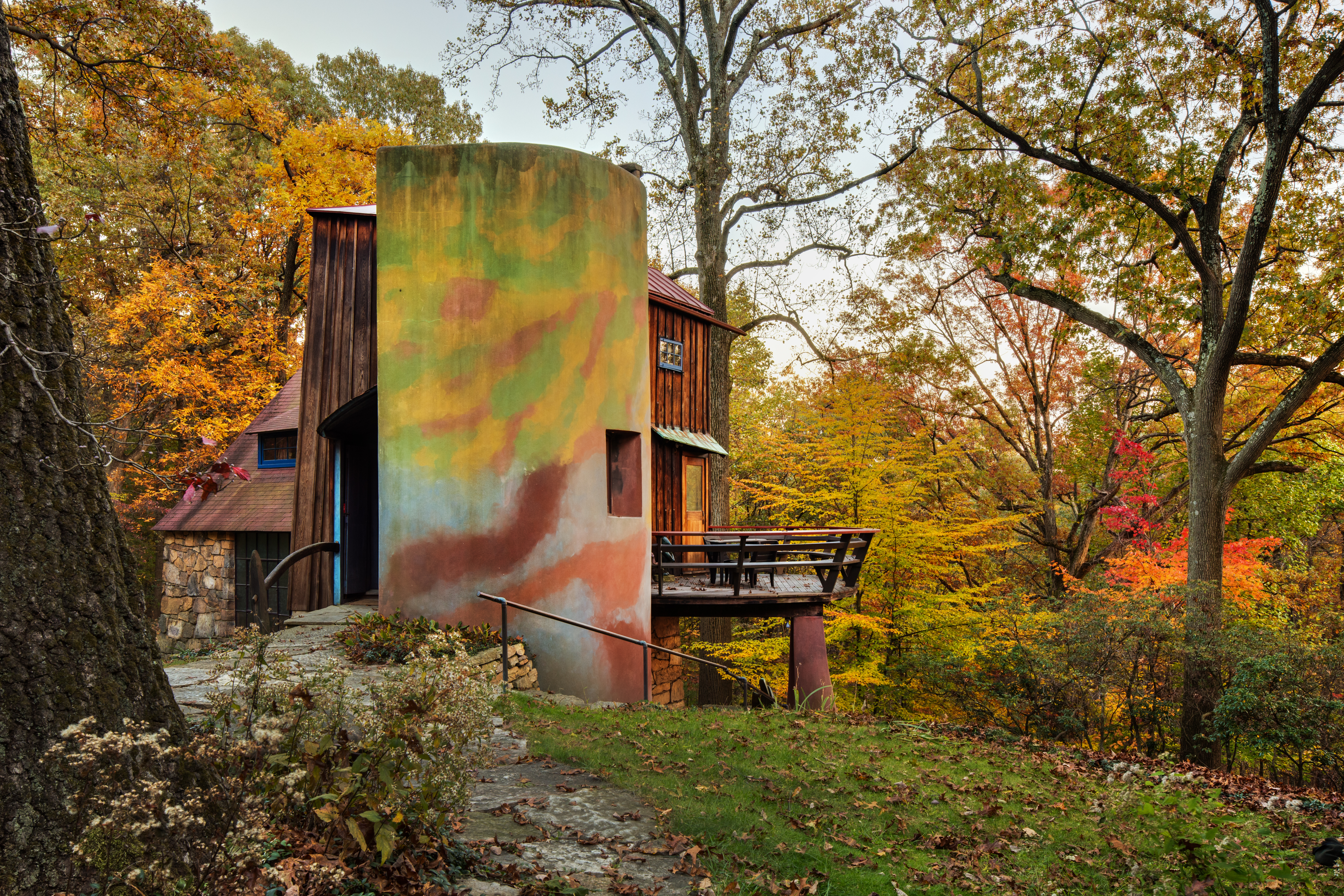 A uniquely structured building amongst beautiful trees with fall leaves.