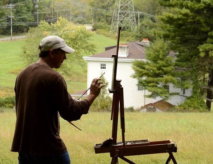 Man standing on a hill painting on a canvas