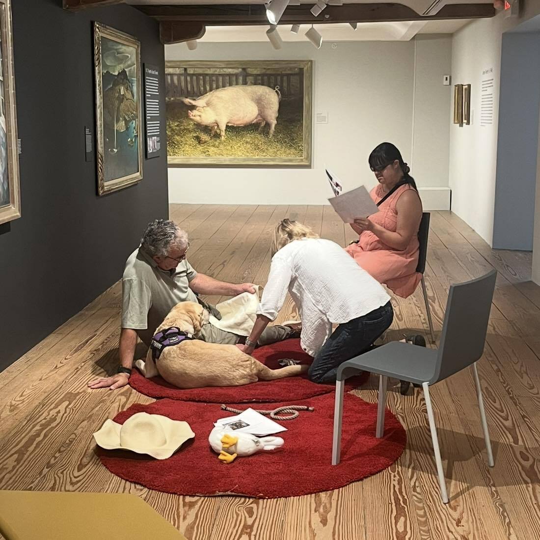 People sitting in a circle looking at art and reading, in an art gallery