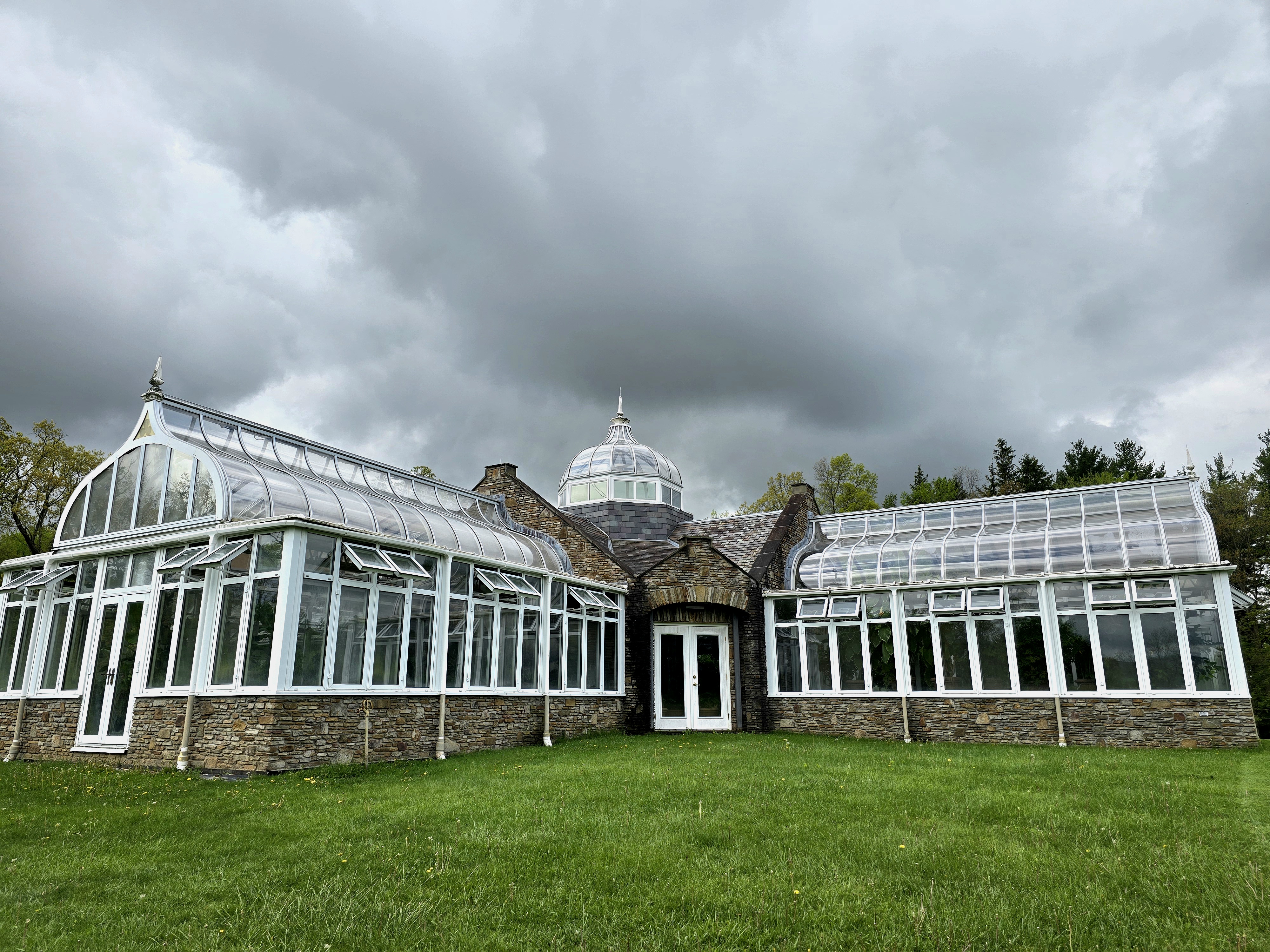 Conservatory in the middle of a field, with grey storm clouds above