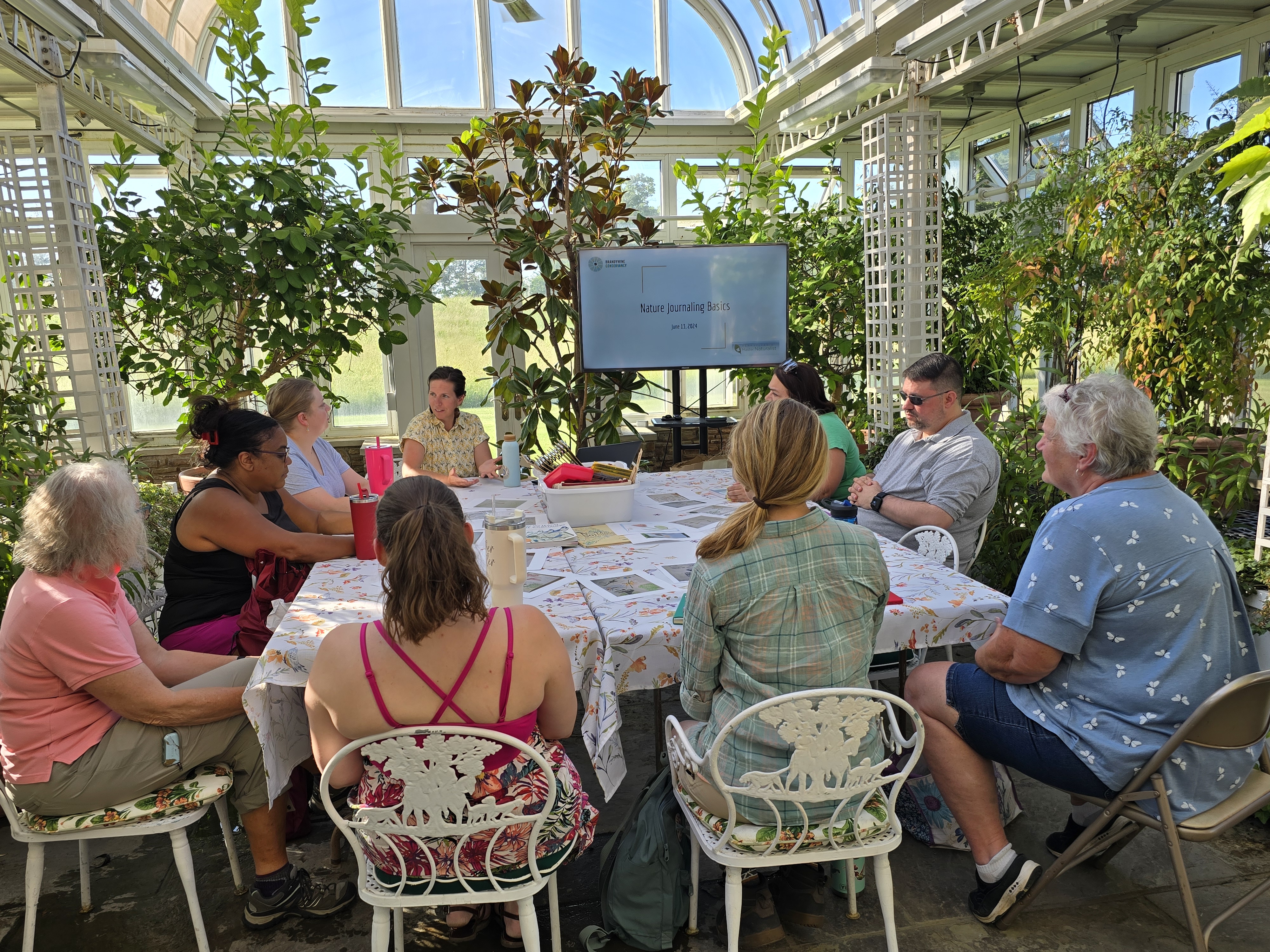 People sitting around a table in greenhouse