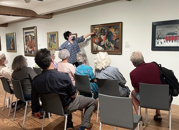 Woman speaking to a group of people about a painting