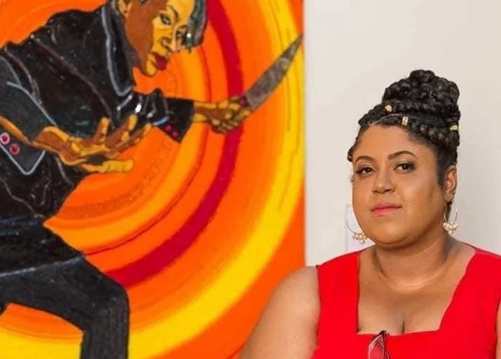 Woman smiling at camera, sitting in front of a painting