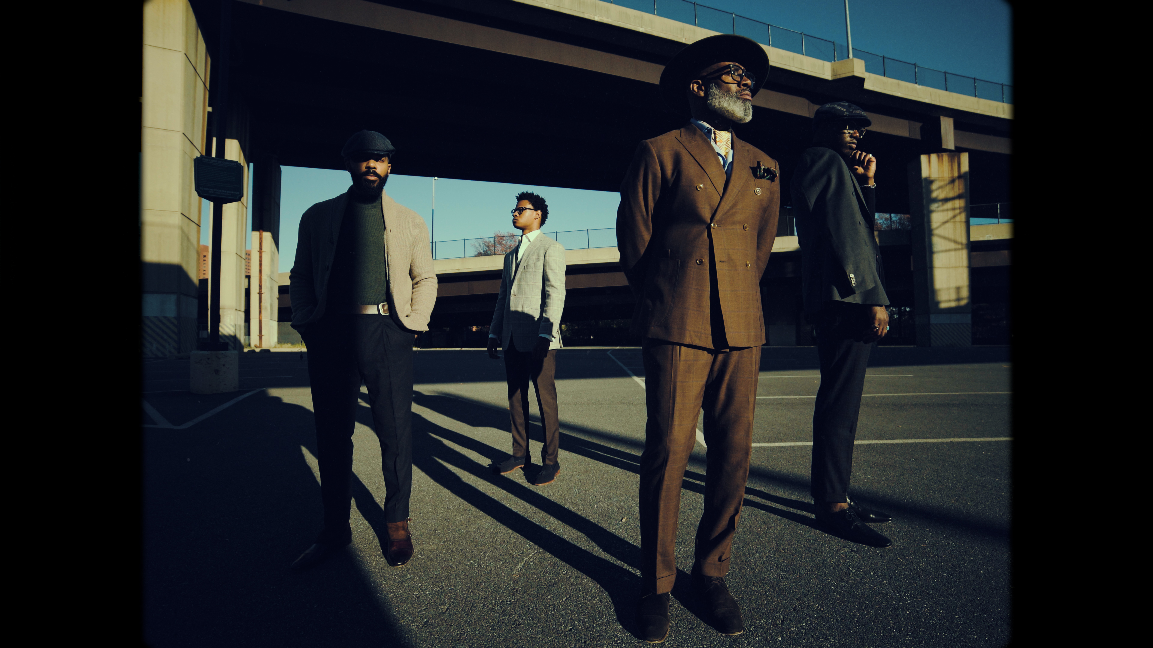 A group of men standing around in different directions, looking into the distance.