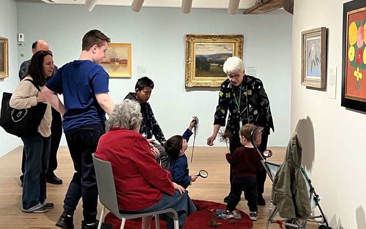 Photo of children siting and looking at paintings in an art museum.