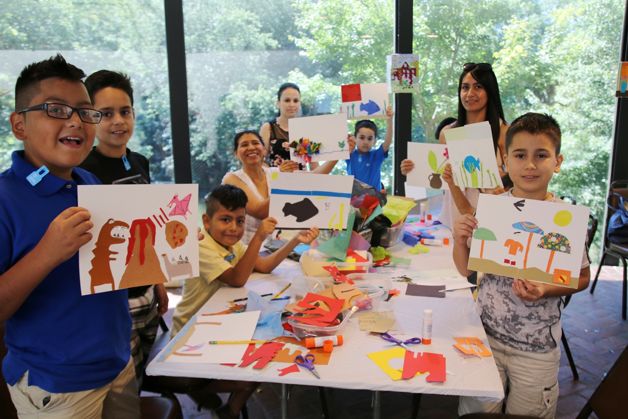 Table full of kids and their families proudly holding up their artwork