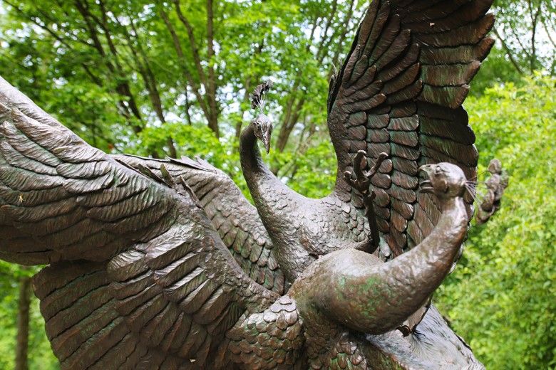 Close up shot of a bronze sculpture of two life-size fighting peacocks in front of the Brandywine's main entrance