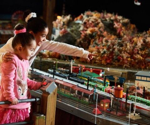 Two kids looking and pointing at the model trains.