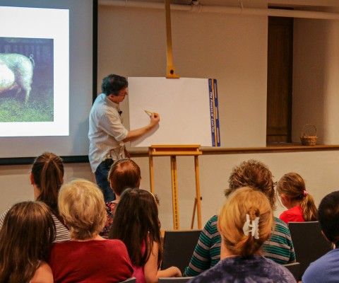 A man sketching in front of an audience.