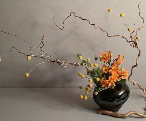 Sogetsu ikebana flower arrangement featuring orange and yellow flowers in a vase
