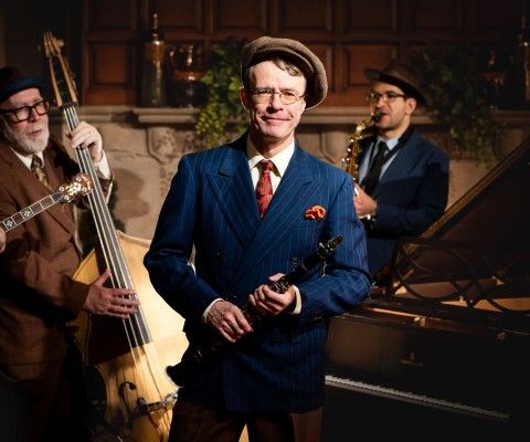 Three musicians stand with their instruments.