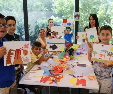 Table full of kids and their families proudly holding up their artwork