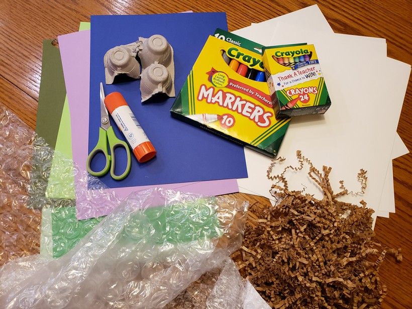 Monster mashup materials, including colorful pieces of construction paper, markers, scissors, glue, and packing materials