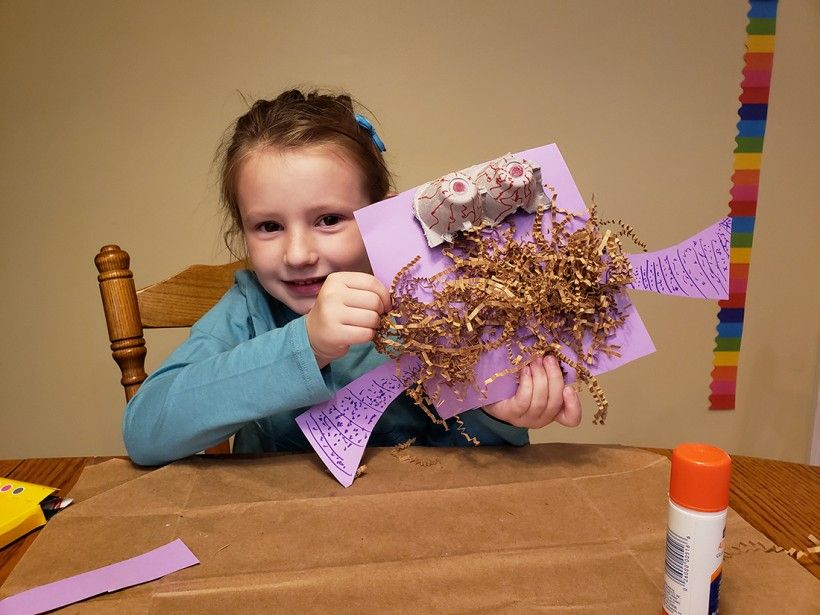 A young girl holding up her monster mashup creation