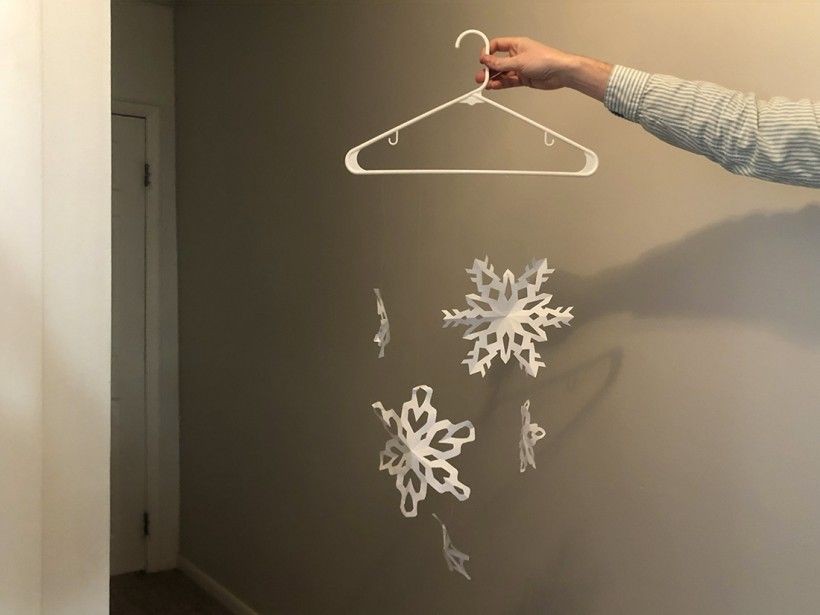 Paper snowflakes attached to a clothes hanger with clear fishing line