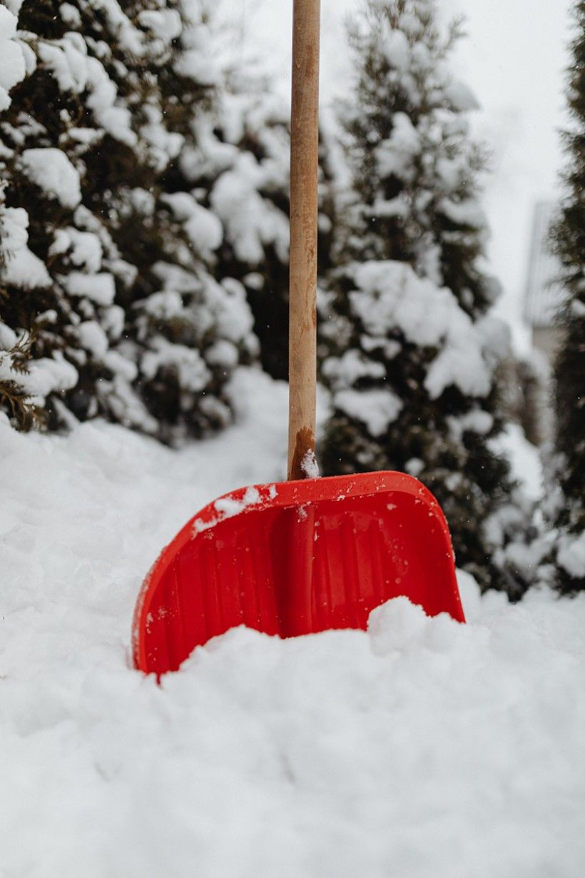Red shovel propped up in snow