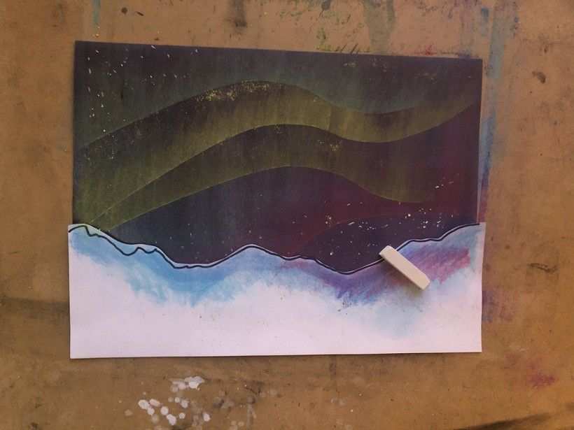 An almost finished northern lights scene with a white piece of chalk pastel on top of the artwork