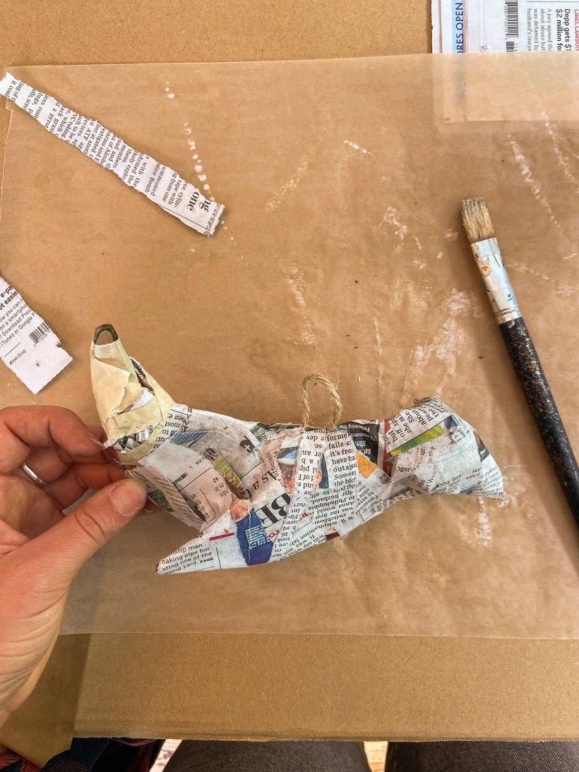 Glueing strips of newspaper to cardboard bird cutout