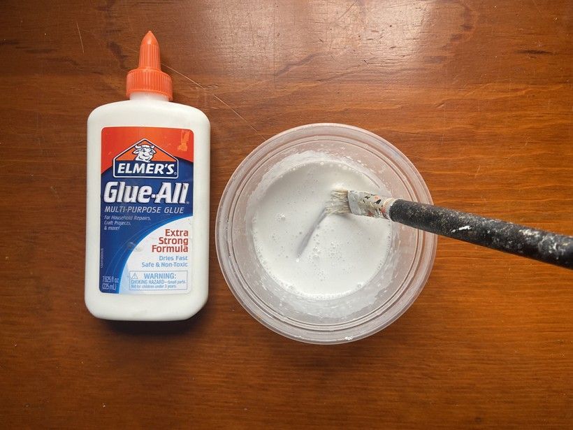 Bottle of Elmer's Glue-All and a cup filled with glue paste