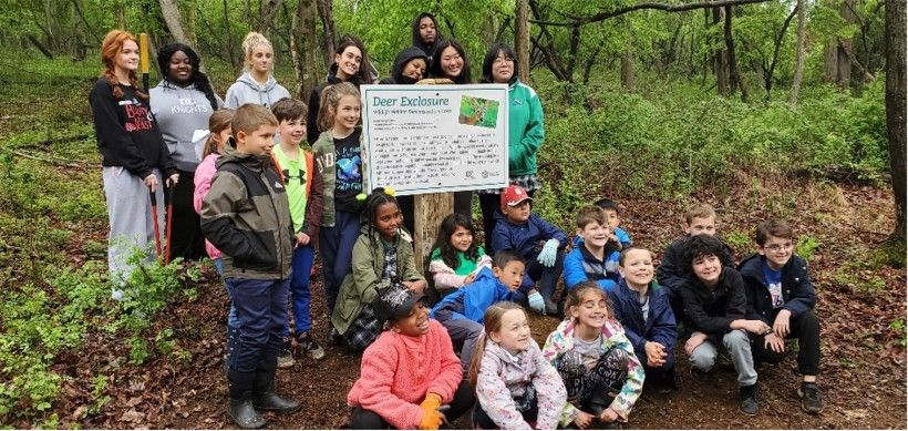 Photo of students from Delaware County Christian School in front of a "Deer Exclosure" sign at Waterloo Mills Preserve