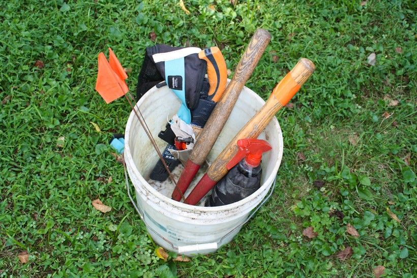 Bucket of tools, include cutters, herbicide, flags, and other garden tools