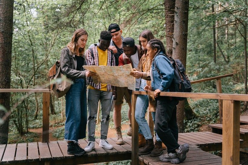 Group of people in nature looking at a map together. Photo by Ivan Samkov