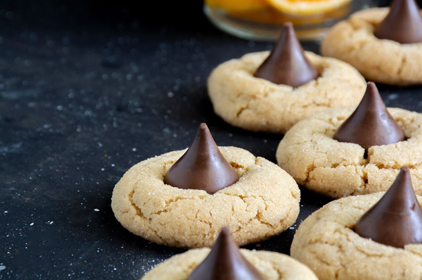 Closeup of peanut butter blossom cookies on a black counter.