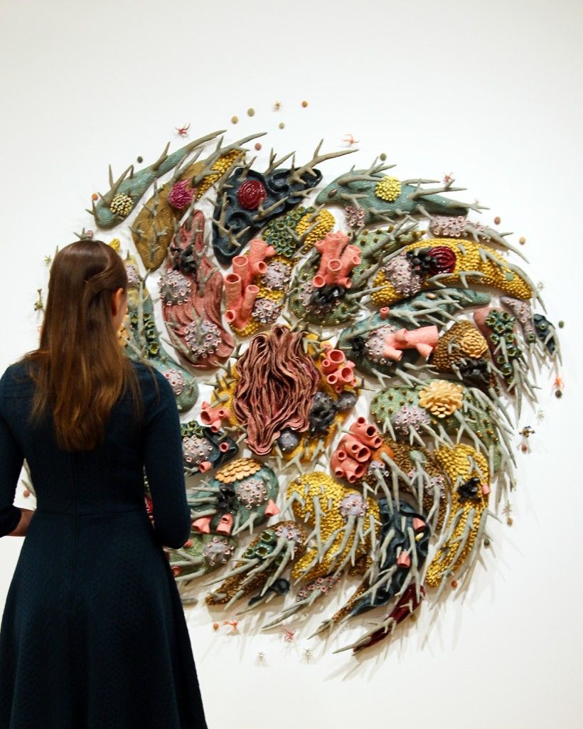 Photo of woman standing in front of Courtney Mattison's swirling "Gyre I" ceramic art wall installation