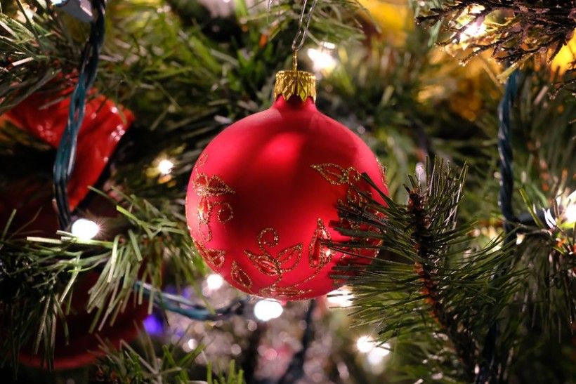 Closeup shot of an artificial Christmas tree with a large red ornament in the center