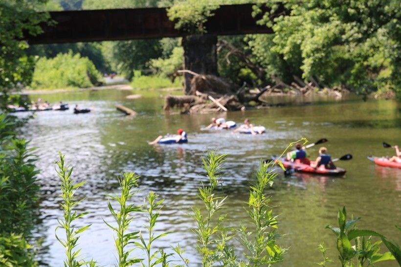 photo of several kayakers and tubers out enjoying the water on a summer day
