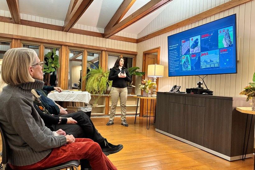 horizontal photo of people seated in a room watching a presentation