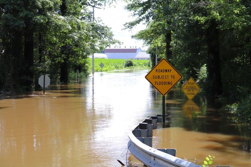 Flooded roadway with yellow triangle sign that says "Roadway subject to flooding"