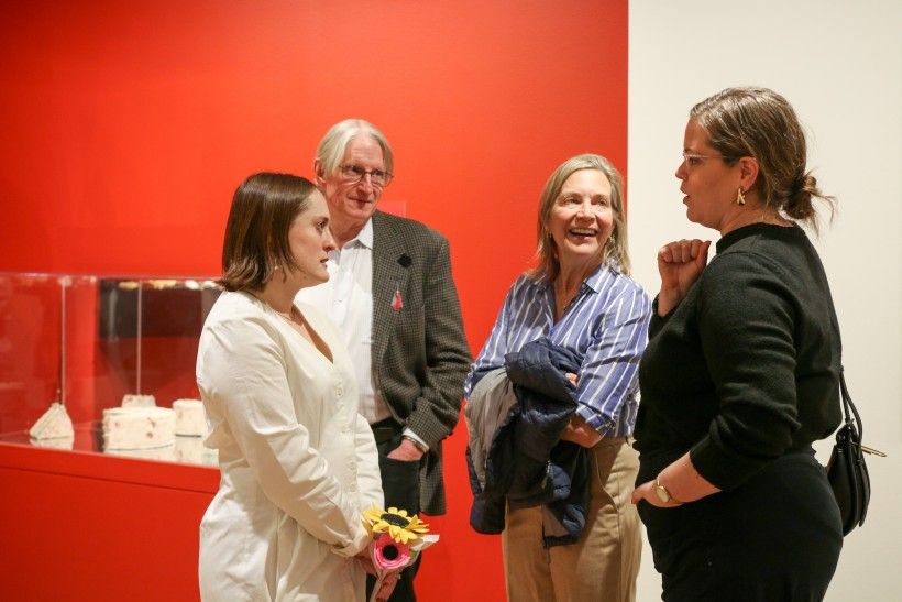 Photo of people standing in a semi circle, discussing art in an gallery. 