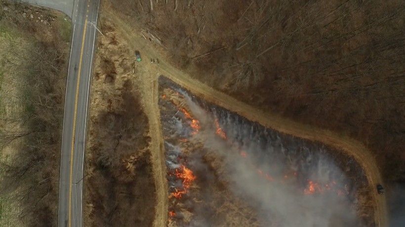 Triangular area mid-burn showing precise control of fire direction so that it can burn in two directions at once, with the flames moving toward the center. Also note how close the road is. Prescribed burns are planned with safety as top priority, so they Triangular area mid-burn showing precise control of fire direction so that it can burn in two directions at once, with the flames moving toward the center. Photo by Jim Moore.