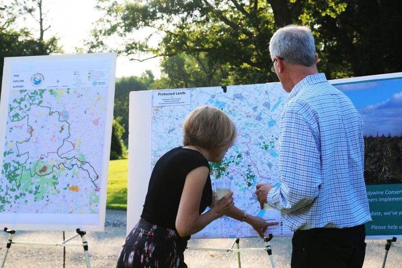 Two people viewing a map of protected lands Farm to Table dinner to celebrate the 50th anniversary of the Brandywine Conservancy