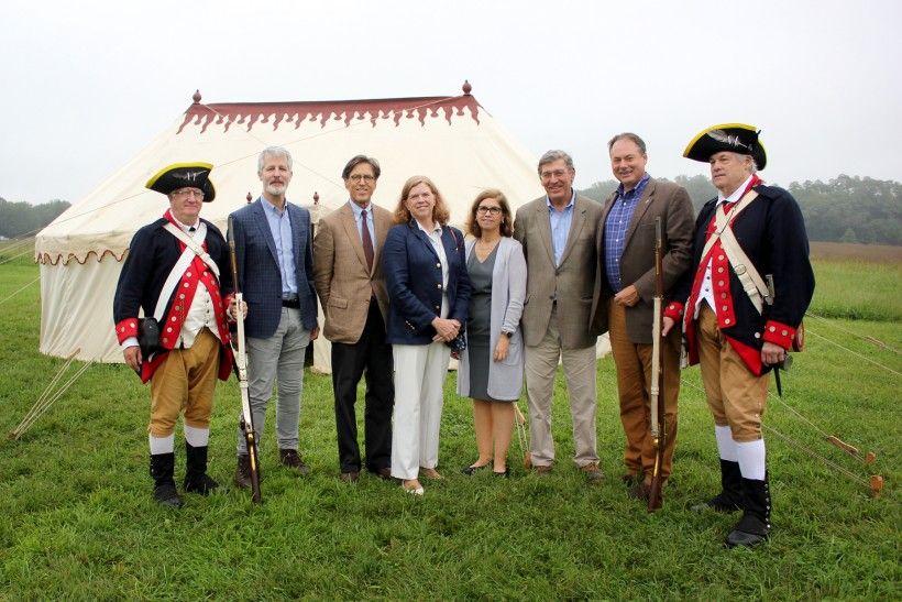 People standing in front of a replica of George Washington's tent, courtesy of the Museum of the American Revolution, with reenactors from the 1st Delaware Regiment bookending the group